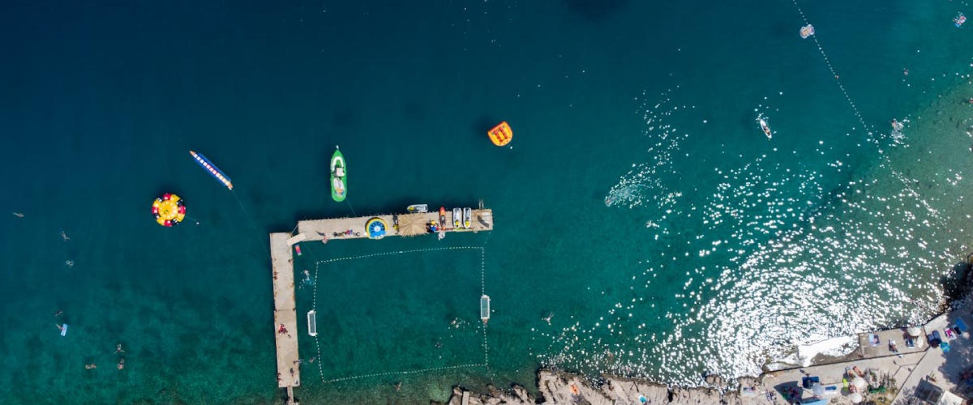 Explore a stunning aerial view of a Croatian pier and clear blue sea, capturing vibrant summer activities.