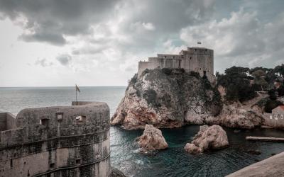 Majestic view of Dubrovnik's medieval forts and rocky coast under dramatic skies.
