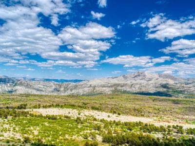 Scenic aerial view of mountains and fields under a bright blue sky in Dalmatia, Croatia.