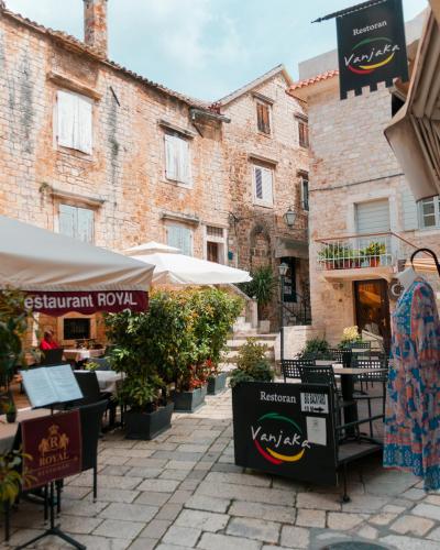 Quaint outdoor dining setup in Trogir, Croatia, featuring rustic stone architecture and restaurant signs.