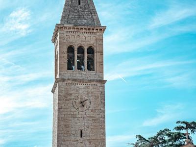 Vertical view of a historic church tower in Novigrad, Croatia against a clear sky.