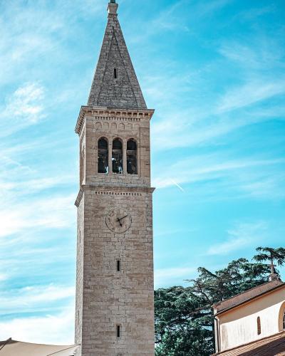 Vertical view of a historic church tower in Novigrad, Croatia against a clear sky.