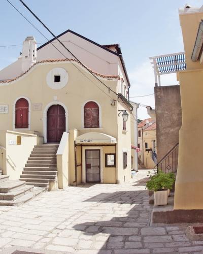 Sunlit alley in Krk, Croatia showcasing charming historic architecture and inviting atmosphere.