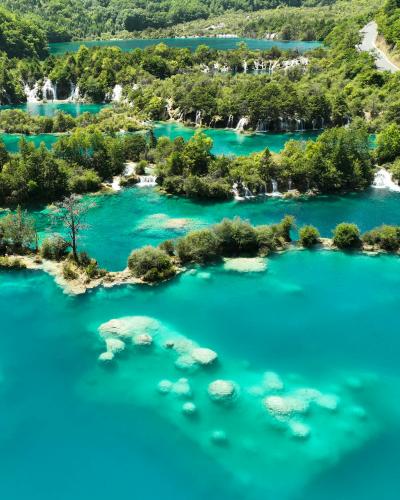 Stunning aerial shot of vibrant turquoise lakes and lush forests at Plitvice Lakes National Park.