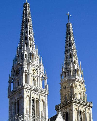 Two iconic Gothic spires of Zagreb Cathedral reaching into a clear blue sky, showcasing Croatian architecture.