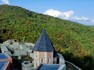 A captivating view of Medvedgrad Castle surrounded by lush hills under a bright, clear sky.
