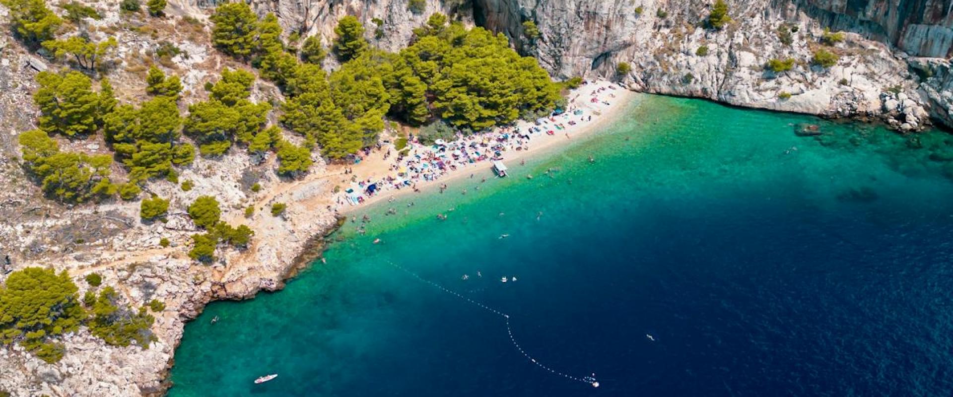Scenic aerial view of the Split-Dalmatia County cliffs and coastline in Croatia, featuring lush greenery and turquoise waters.