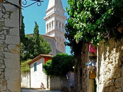 Explore the quaint alleyways of Rovinj leading to the iconic Church of St. Euphemia on a sunny day.