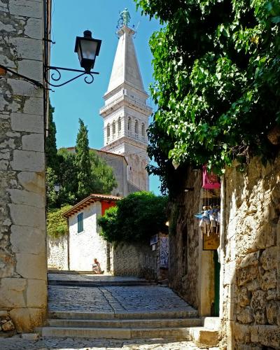 Explore the quaint alleyways of Rovinj leading to the iconic Church of St. Euphemia on a sunny day.