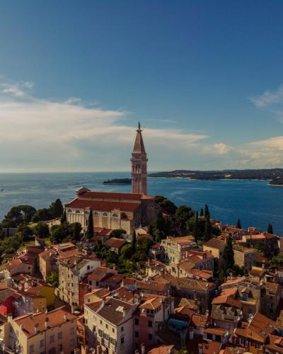 Free Aerial photo of Rovinj, Croatia, highlighting its historic church tower and coastal scenery. Stock Photo