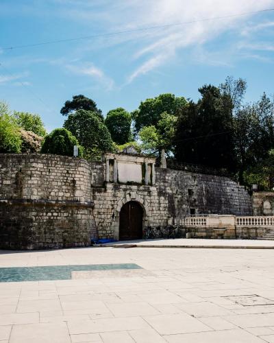 Explore the ancient stone gateway in Queen Jelena Madijevka Park, Zadar, with vibrant greenery and clear skies.