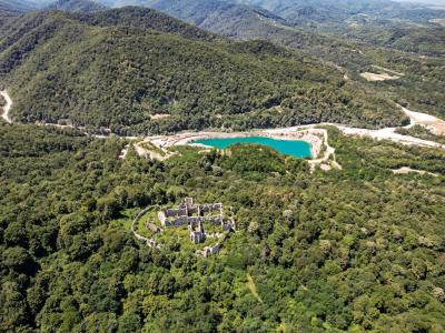 A spectacular aerial view of ancient ruins surrounded by lush greenery and a turquoise lake in Orahovica, Croatia.