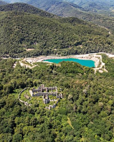 A spectacular aerial view of ancient ruins surrounded by lush greenery and a turquoise lake in Orahovica, Croatia.