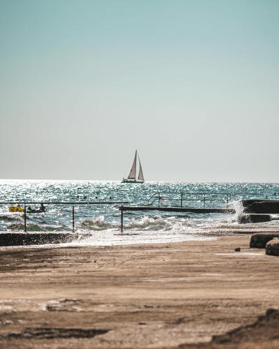 Free A tranquil view of a sailing boat on the shimmering sea under a clear sky, perfect for travel and leisure themes. Stock Photo