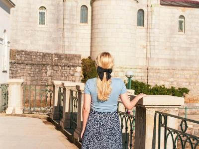 A woman walks past historic architecture in Croatia, capturing a vintage summer aesthetic.