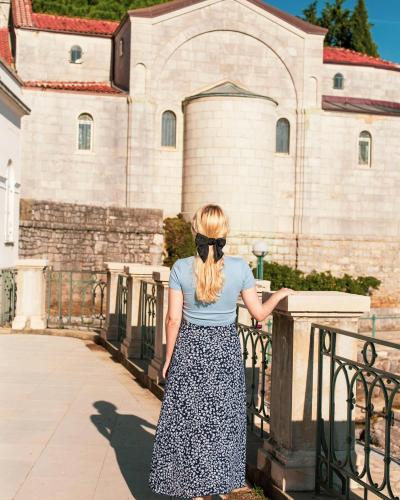 A woman walks past historic architecture in Croatia, capturing a vintage summer aesthetic.