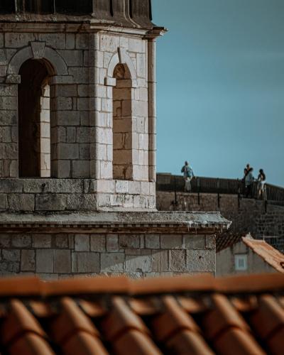 Close-up of Dubrovnik's historic stone tower and city walls under a clear sky.