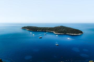 Stunning aerial view of an island in Dubrovnik, Croatia surrounded by turquoise waters and boats.
