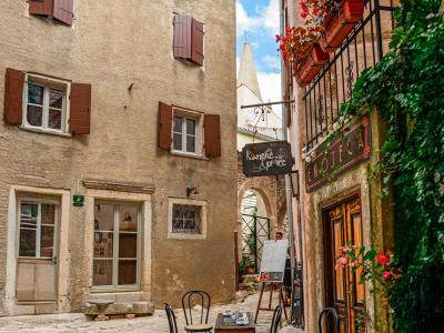 Picturesque scene of a quaint street in Bale, Croatia featuring a cozy outdoor café and historic architecture.