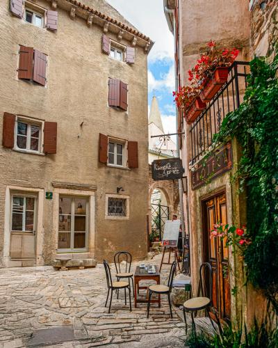 Picturesque scene of a quaint street in Bale, Croatia featuring a cozy outdoor café and historic architecture.