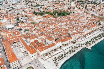 Stunning aerial shot of Split's historic buildings and coastline in Croatia, featuring orange rooftops along the Adriatic Sea.
