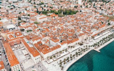 Stunning aerial shot of Split's historic buildings and coastline in Croatia, featuring orange rooftops along the Adriatic Sea.