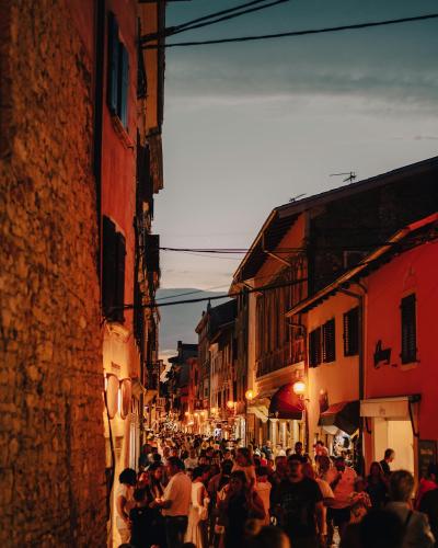 Lively street in a Croatian town at twilight filled with people and historic architecture.