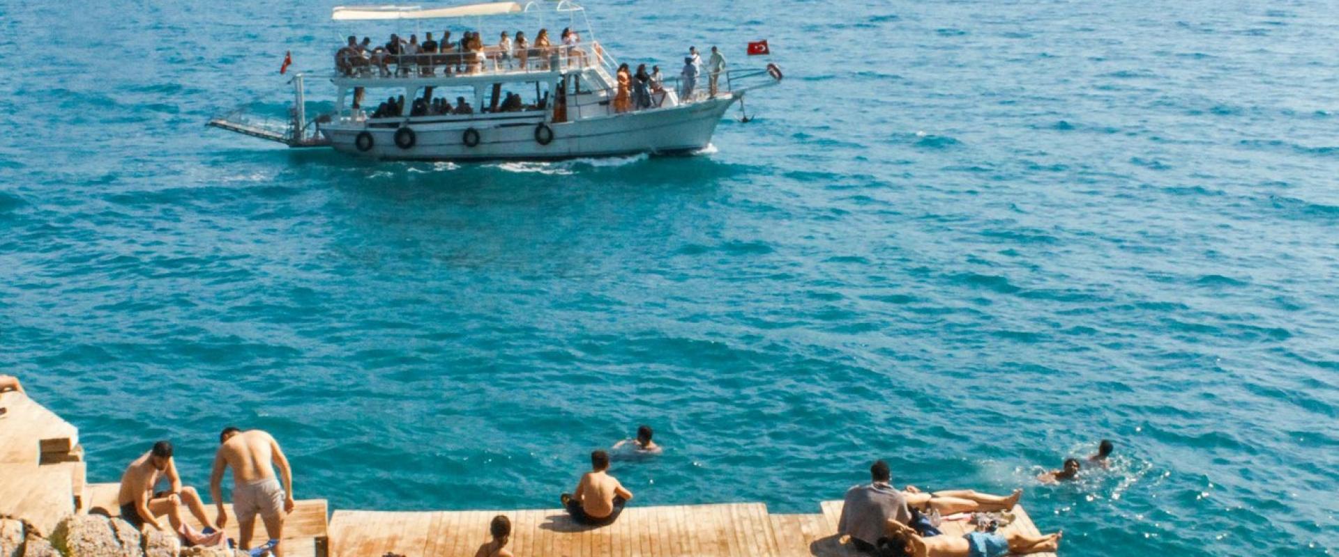 Blue Adriatic Sea with people on docks and tour boat, Croatian coast.
