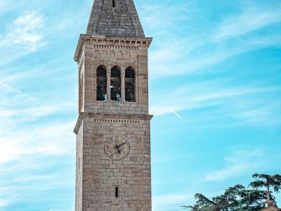 Vertical view of a historic church tower in Novigrad, Croatia against a clear sky.
