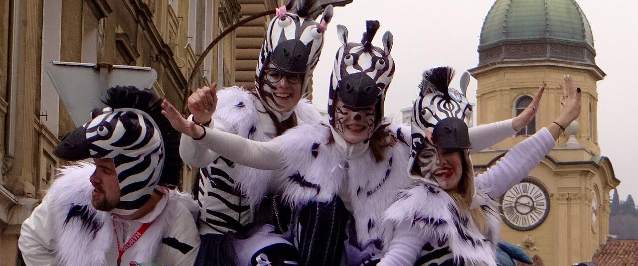 Masked carnival group on a float in front of the City Clock Tower on the Korzo in Rijeka