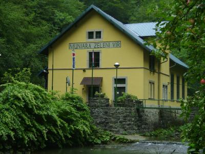 The yellow Munjara Zeleni Vir power station building by the stream