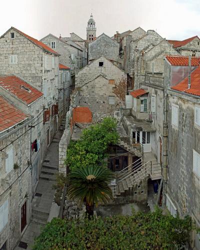 A panoramic view from an elevated position overlooking the narrow streets, stone buildings with terracotta roofs, and the sea of the Old Town of Korčula, Croatia.