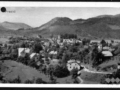 A vintage black and white postcard showing a panoramic view of a small village nestled in a valley with forested hills in the background, labeled "Prezid" in the top left corner.